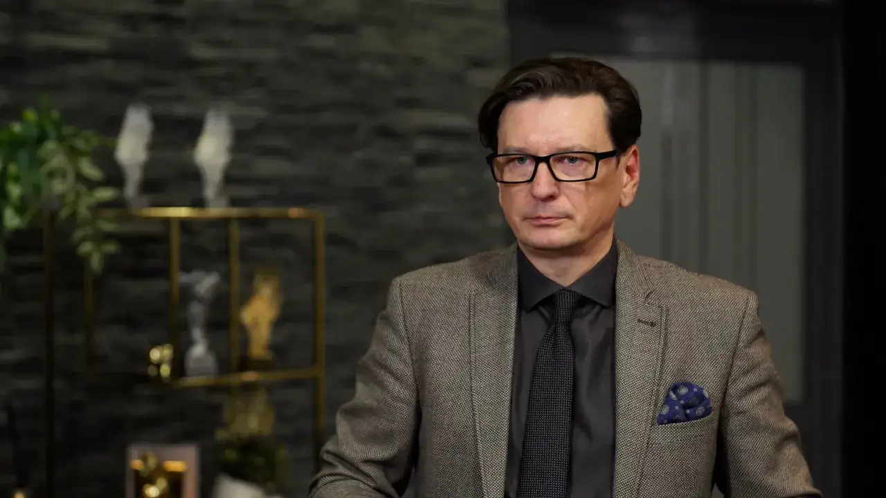 Mężczyzna w okularach i eleganckim garniturze, który może udzielić wskazówek, jak zostać agentem nieruchomości.