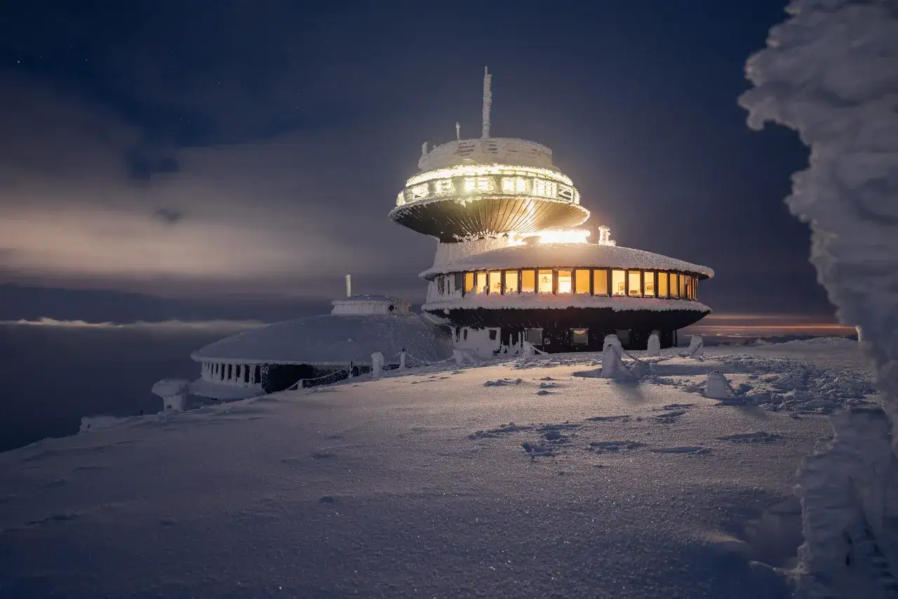 Zimowy szlak na Śnieżkę. Obserwatorium w mroźnej scenerii, oświetlone nocą, otoczone śniegiem i lodem.