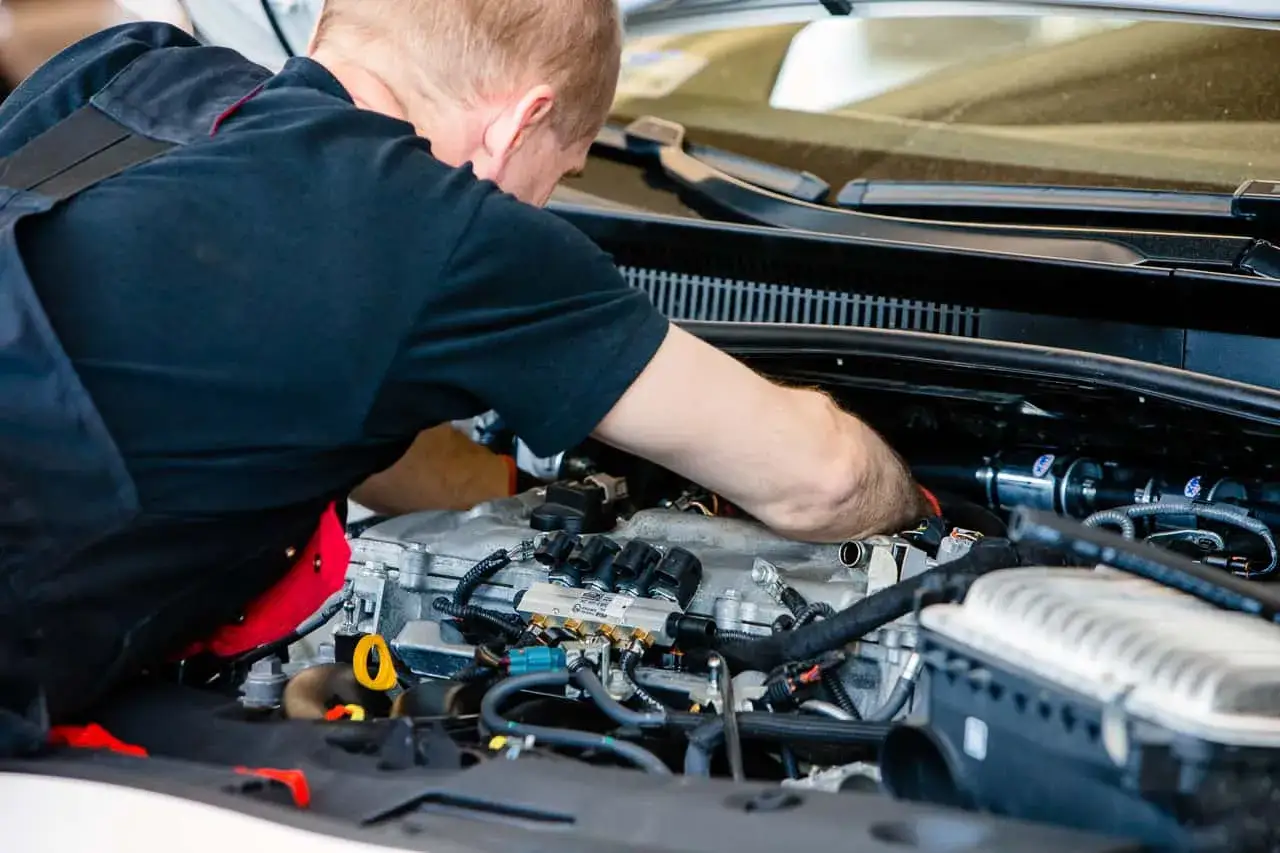 Mechanik pracuje przy silniku, instalując system gazu butan.