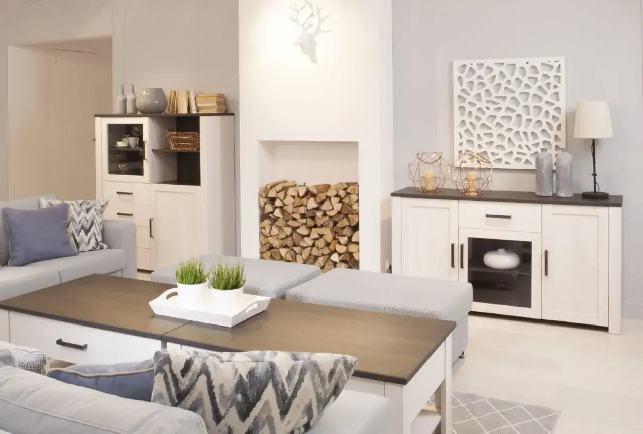 Przytulny salon w stylu prowansalskim z kominkiem, drewnem i jasnymi meblami.