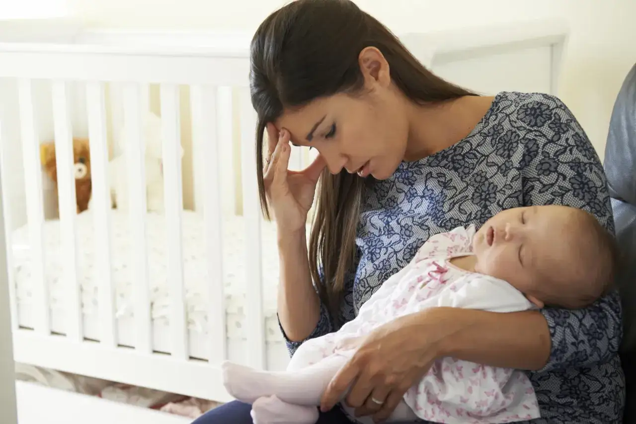 zmęczona ale spokojna mama przytula niemowlę w fotelu