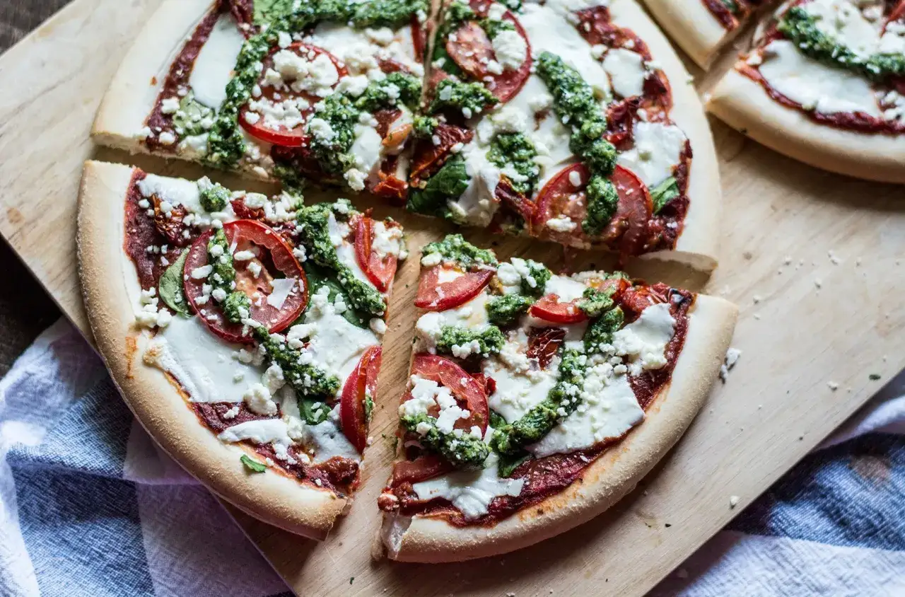 Pyszna pizza ze szpinakiem, pomidorami i fetą, polana zielonym pesto. Idealna na szybki obiad.