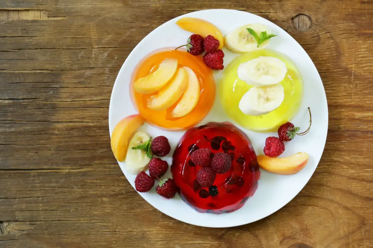 Kolorowe galaretki z owocami na talerzu. Zastanawiasz się, jak długo zastyga galaretka? Ta wygląda na gotową do jedzenia!