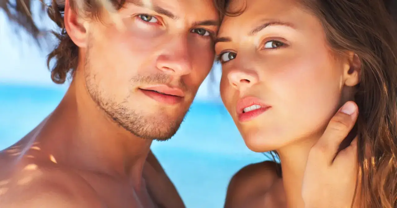 Zbliżenie na twarze pary, kt&oacute;ra wydaje się cieszyć nowym związkiem po rozstaniu. Słońce i plaża w tle.