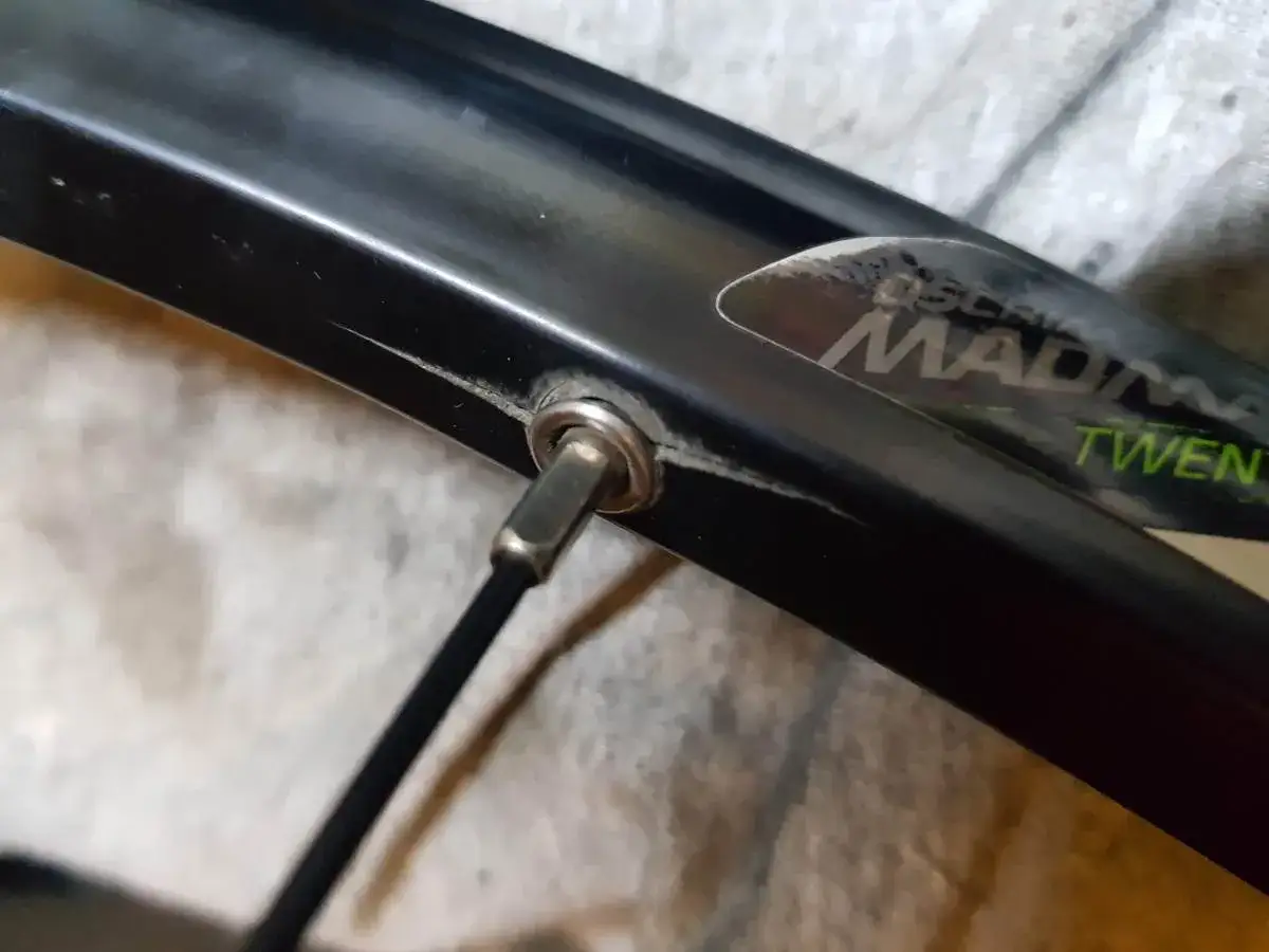 Narzędzie do prostowania felgi rowerowej wkręcone w nyplę. Naprawa lekko wgniecionej obręczy.