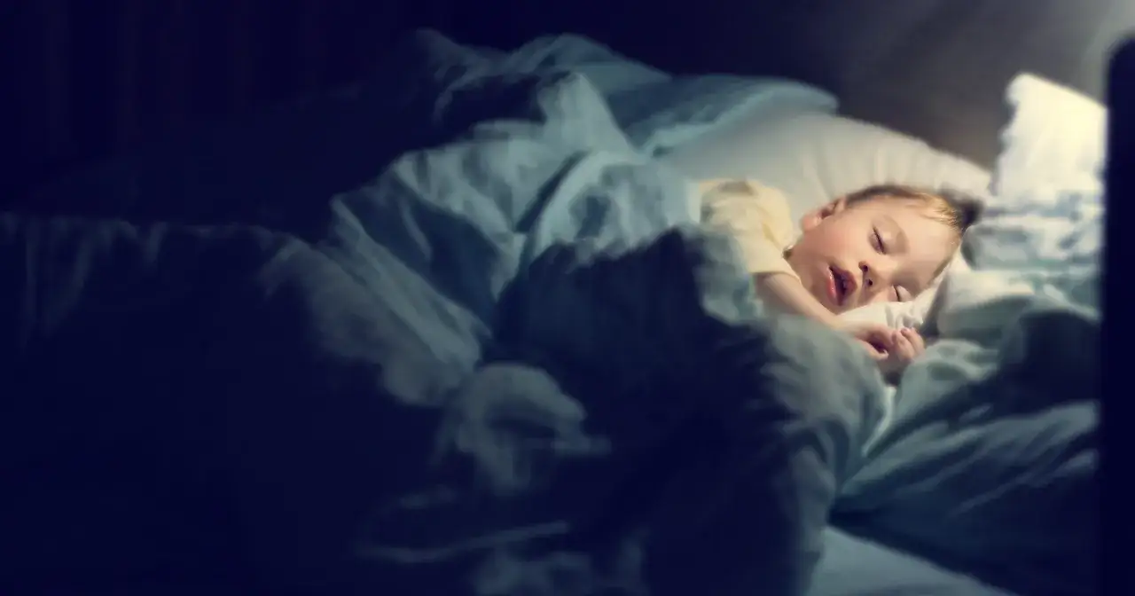 Małe dziecko śpi w łóżku, otulone kołdrą. Czy to sen, czy już początek odpowiedzi na pytanie, dlaczego dziecko lunatykuje?