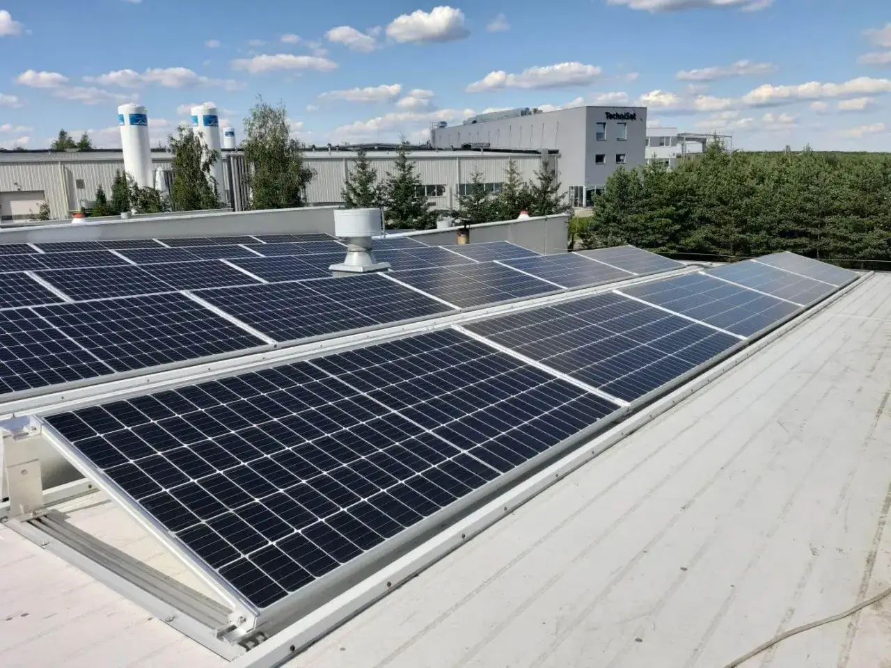 Panele fotowoltaiczne na dachu budynku przemysłowego. Rozwój fotowoltaiki w Polsce nabiera tempa, zapewniając czystą energię.