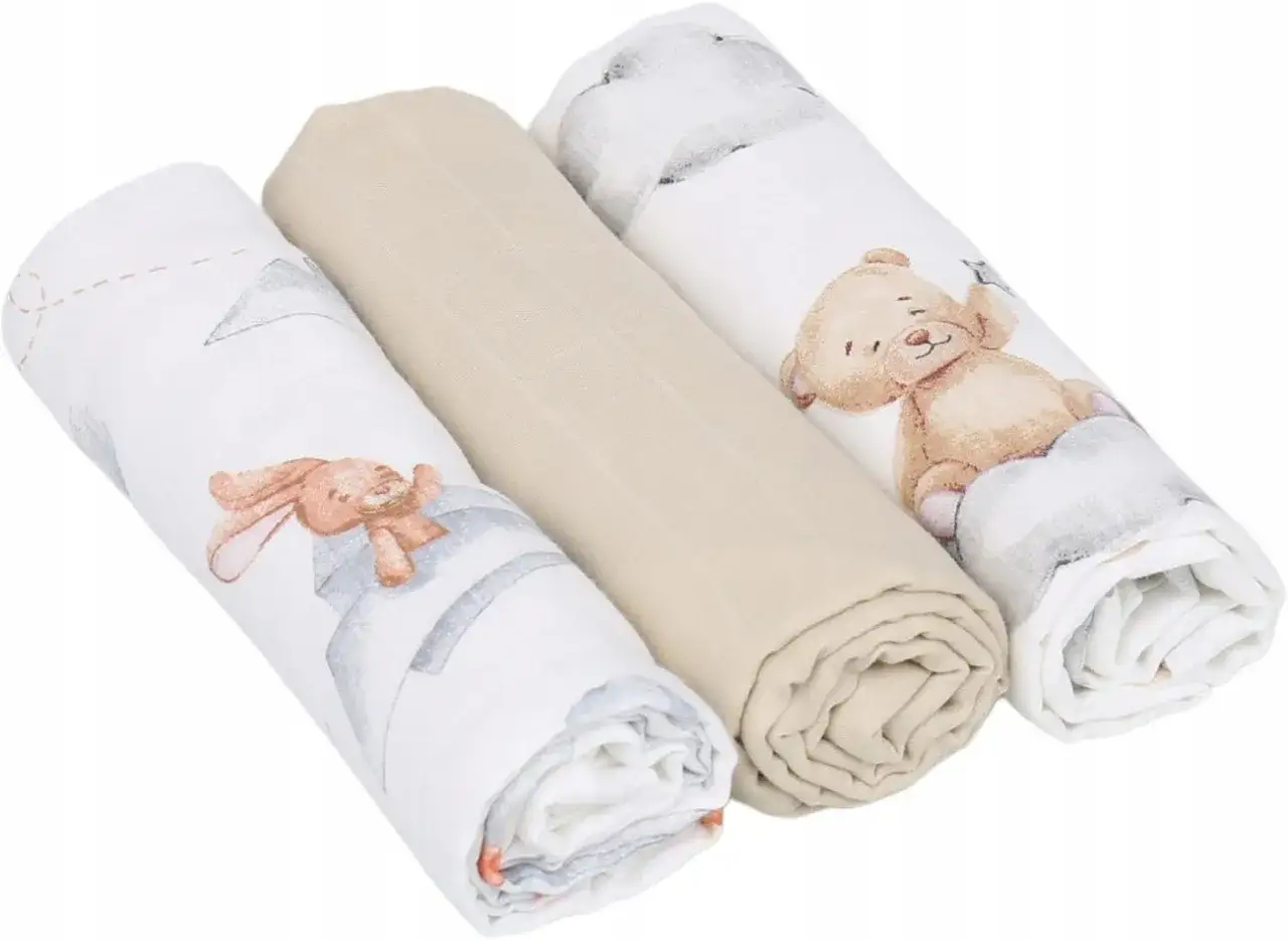 Trzy zwinięte pieluszki muslinowe: dwie z uroczymi zwierzątkami (kr&oacute;lik, miś), jedna gładka, beżowa.