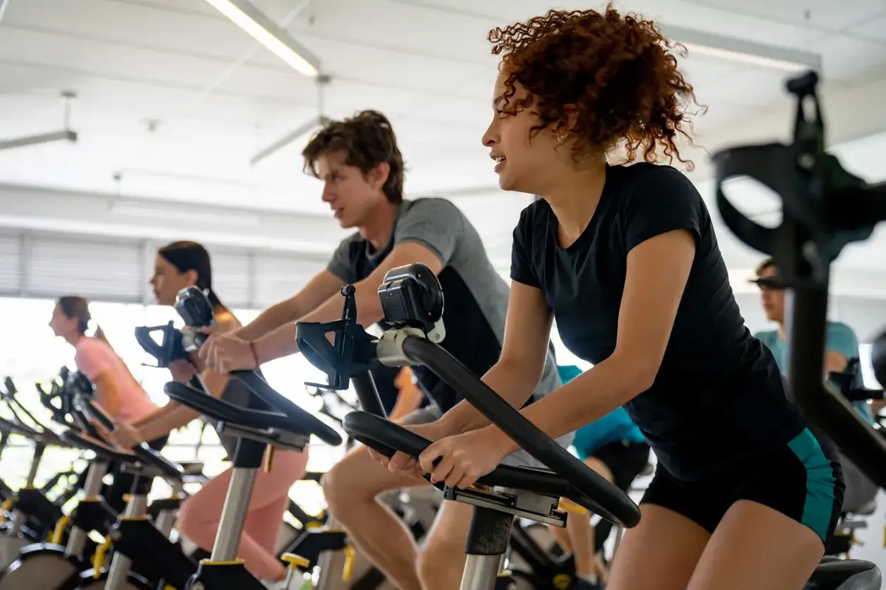Intensywny trening na rowerach stacjonarnych. Grupa ludzi ćwiczy, co to jest spinning, poprawiając kondycję.