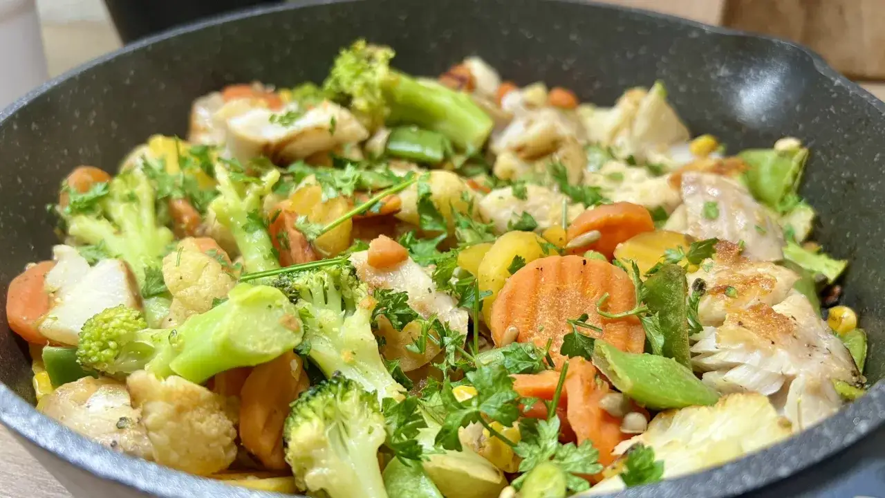 Lekkostrawny obiad dla matki karmiącej: ryba z warzywami na patelni &ndash; brokuły, marchewka, kalafior, fasolka szparagowa, ziemniaki, kukurydza, posypane natką pietruszki.