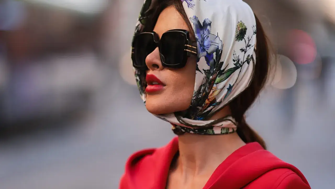 Elegancka kobieta w kwiecistej chuście na głowę i okularach przeciwsłonecznych. Chusta na głowę stylizacje w stylu retro.