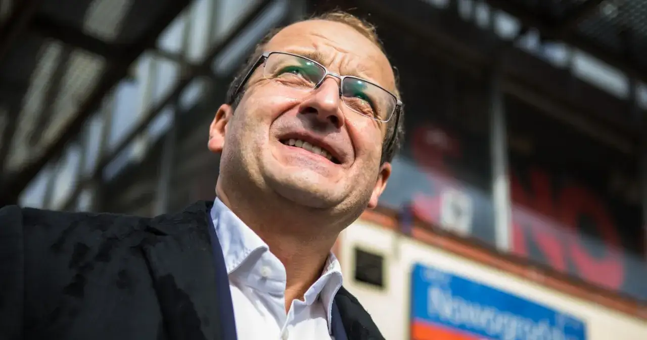 Robert z Kabaretu Moralnego Niepokoju w okularach, z uśmiechem na twarzy, patrzy w górę.