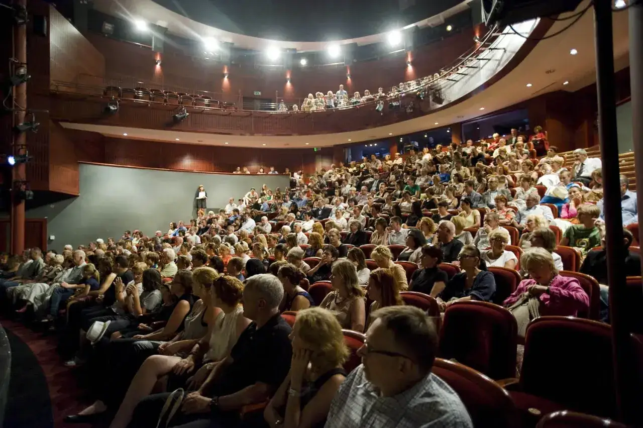 Widownia teatru wypełniona po brzegi. Czekają na rozpoczęcie spektaklu, zastanawiając się, ile trwa przedstawienie w teatrze.