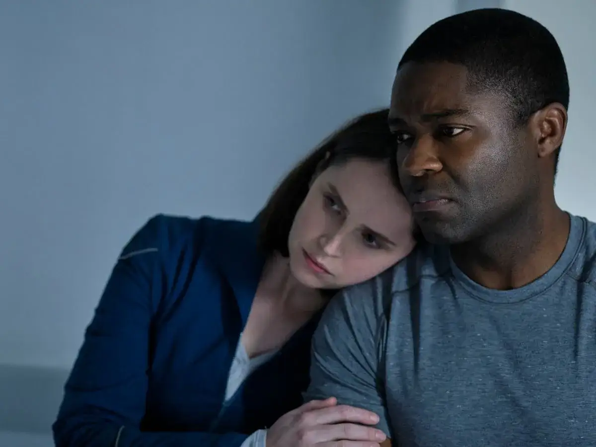 Kobieta opiera głowę na ramieniu mężczyzny. Ich twarze wyrażają smutek, jakby patrzyli na niebo o północy.