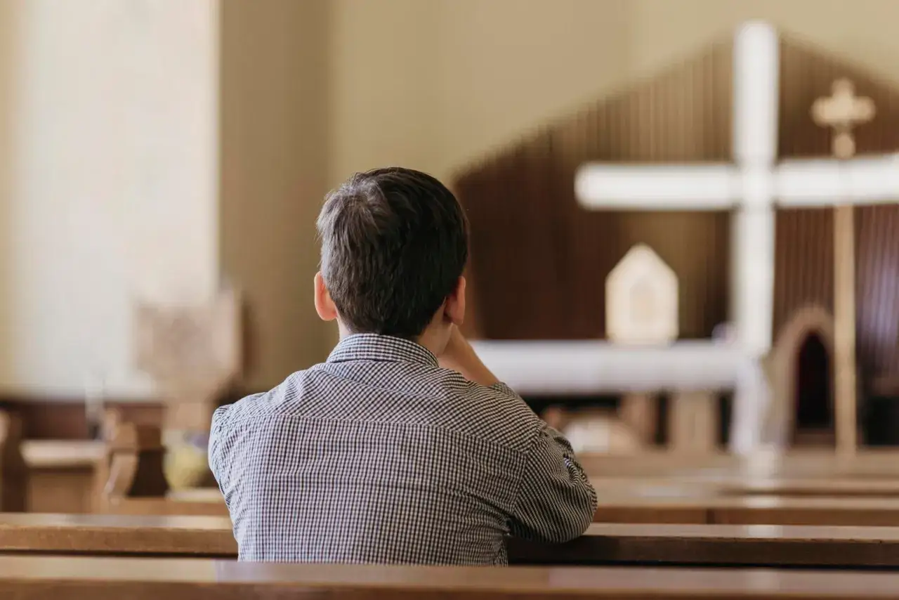 Chłopiec w kościele, zaduma nad praktykami religijnymi. Badanie CBOS pokazuje, że młodzi ludzie nadal szukają duchowości.