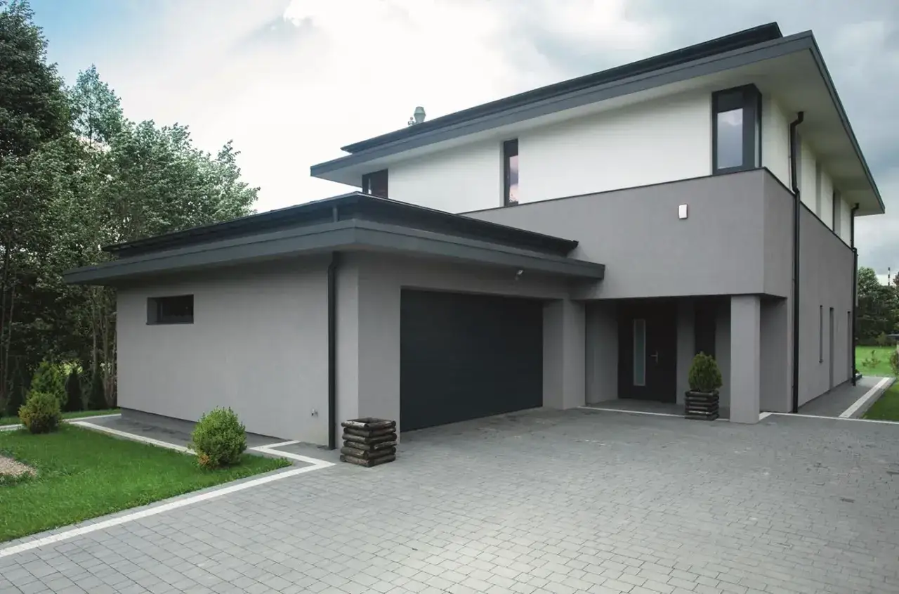 Nowoczesny dom z garażem, wykończony tynkiem w odcieniach szarości. Knauf strefa koloru podkreśla jego architekturę.