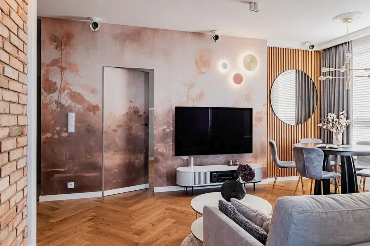 Nowoczesne fototapety do małego salonu tworzą przytulną atmosferę. Wnętrze z cegłą, drewnianą podłogą i okrągłym lustrem.