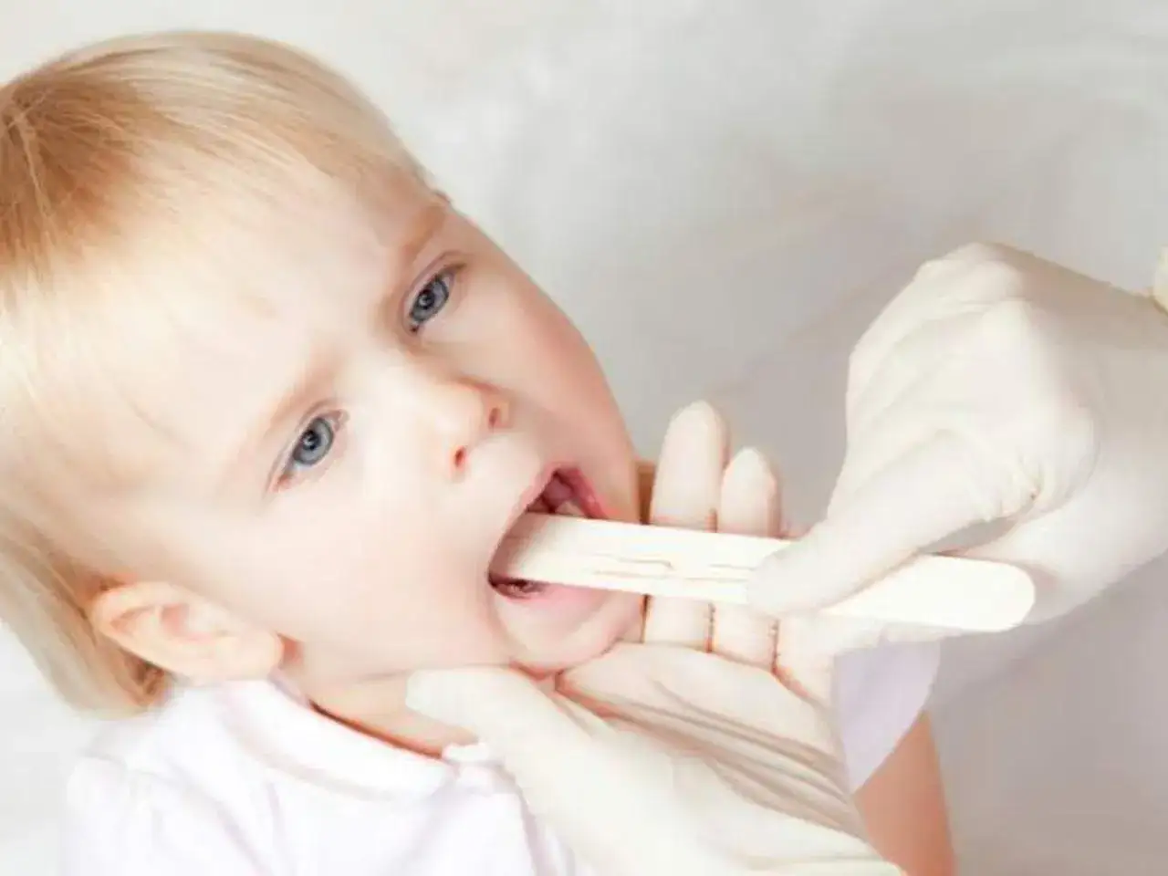 Lekarz bada gardło dziecka. Czas trwania zapalenia krtani może być r&oacute;żny, ale ważne jest szybkie rozpoznanie.