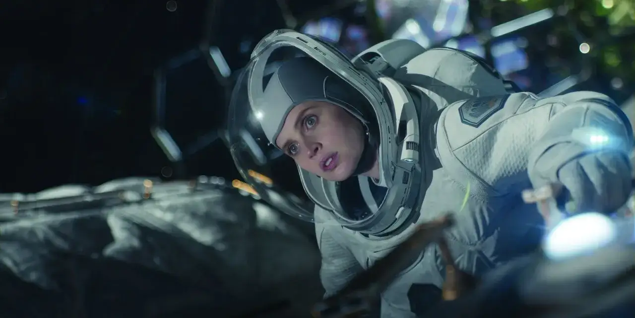 Astronautka w skafandrze kosmicznym, zdeterminowana, pracuje w ciemnościach, jakby pod niebem o północy.