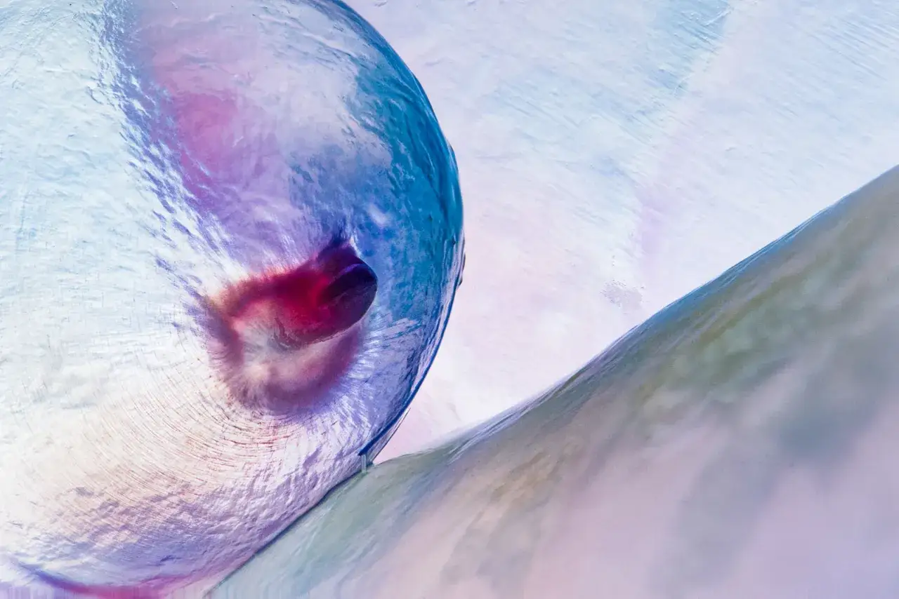 Abstrakcja fotografia: błękitno-fioletowa, p&oacute;łprzezroczysta forma z ciemnym wgłębieniem, otoczona pastelowym tłem.