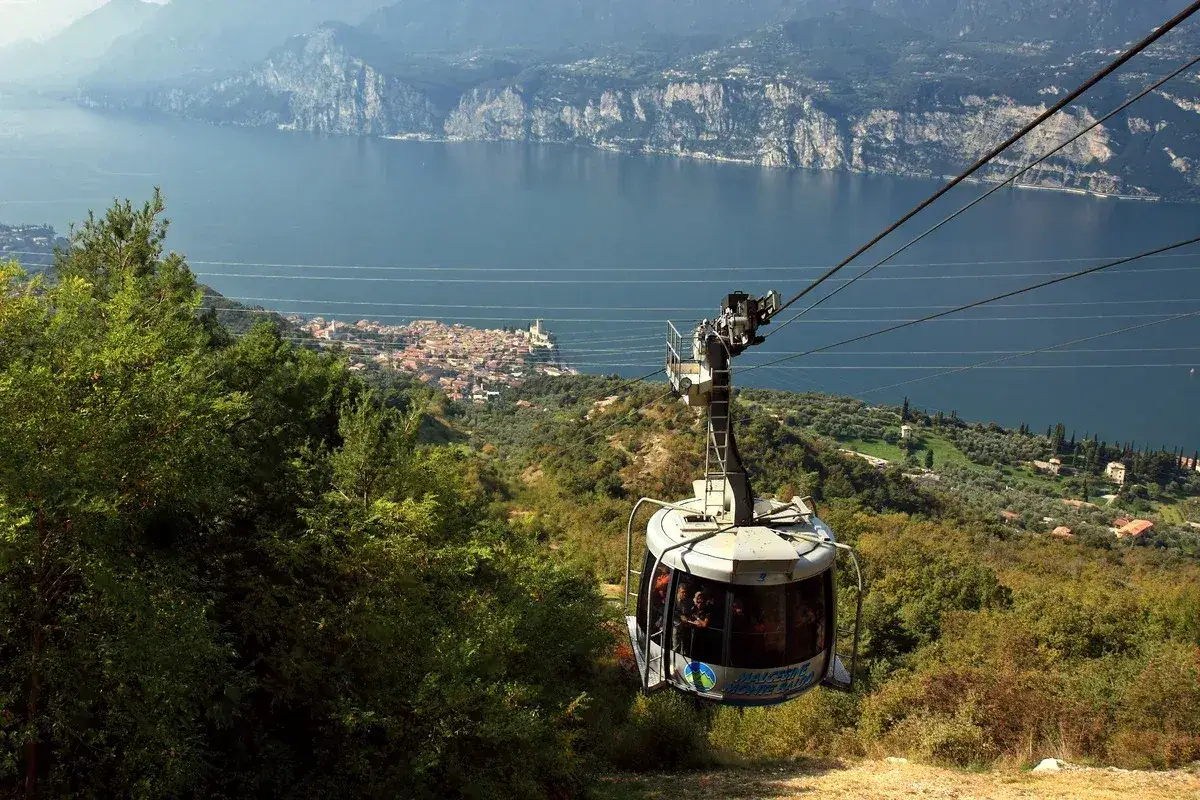 Kolejka linowa na Monte Baldo zjeżdża w d&oacute;ł, ukazując malowniczą panoramę jeziora Garda i miasteczka.