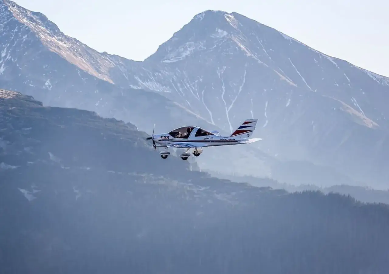 Widok na Tatry z samolotu. Mały samolot leci na tle majestatycznych, ośnieżonych gór.