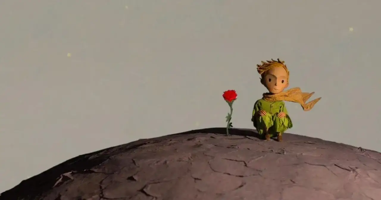 Mały Książę, zastanawiając się, dlaczego opuścił swoją planetę, siedzi obok swojej ukochanej r&oacute;ży na skalistym globie.