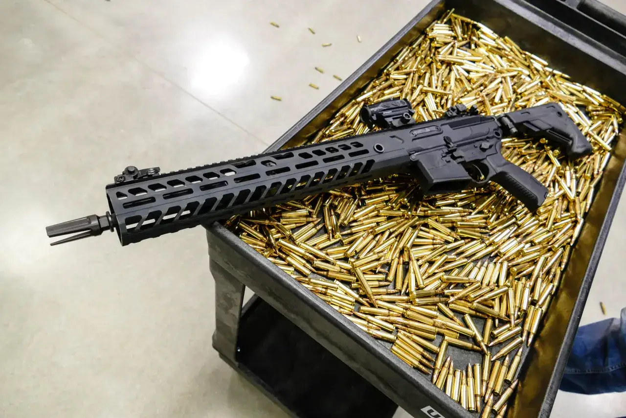 Czarny karabin leży na tacce pełnej naboi. Czy myśliwy może pożyczyć broń od kolegi?