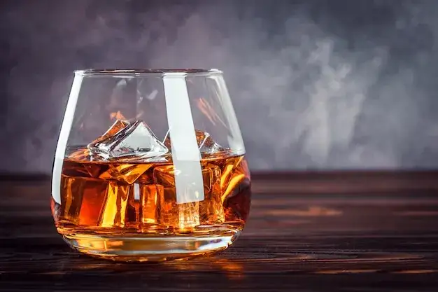 kieliszek koniaku i szklanka whisky z lodem