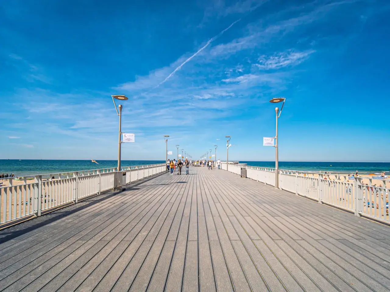 Spacer po molo w Kołobrzegu. Ludzie spacerują, a morze i plaża zachęcają do odpoczynku. Czy molo w Kołobrzegu jest płatne? Nie, wejście jest darmowe!
