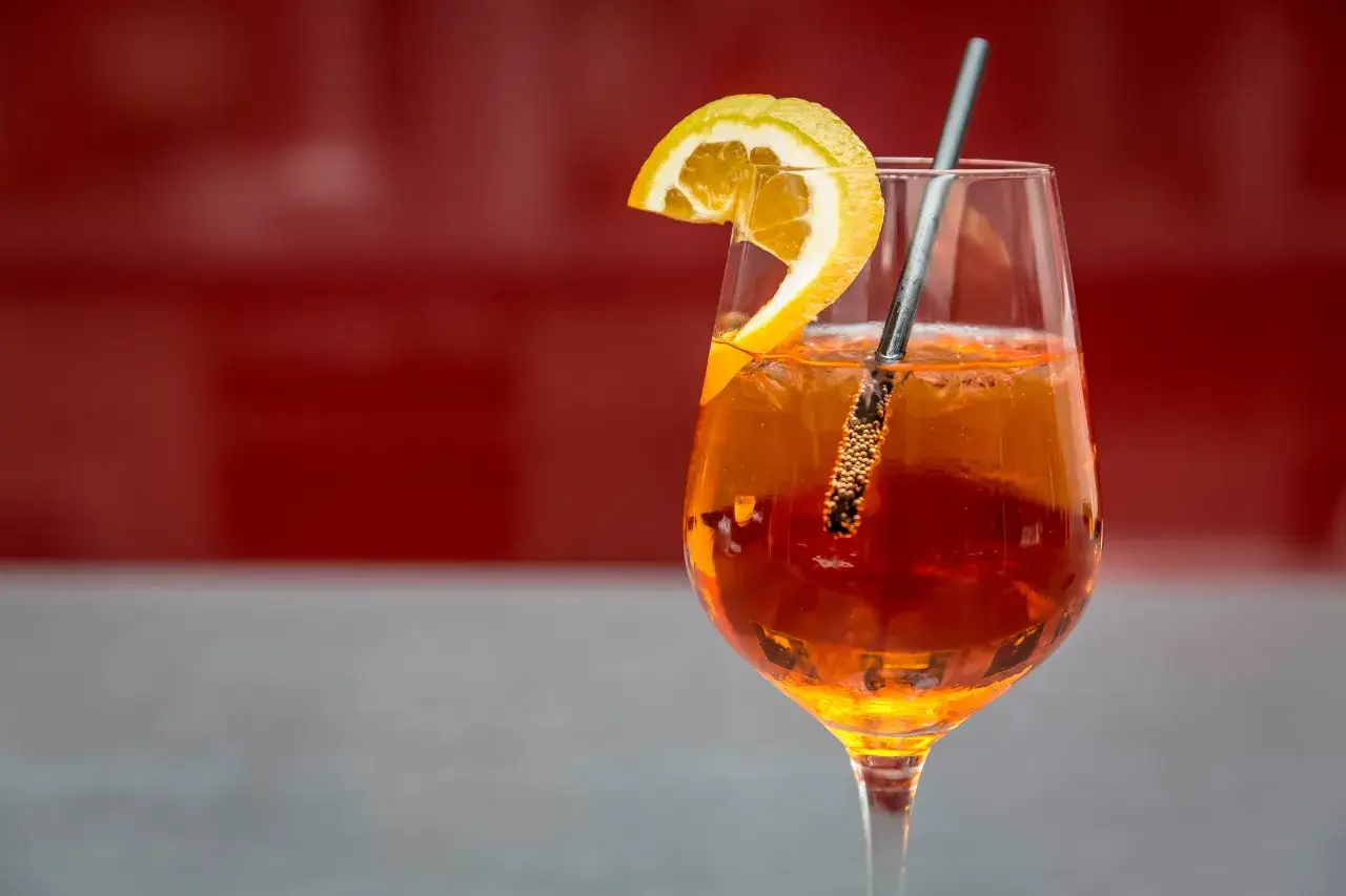 Jak zrobić drinka z aperolu? Orzeźwiający Aperol Spritz z plasterkiem pomarańczy i kostkami lodu. Idealny na letnie popołudnie.
