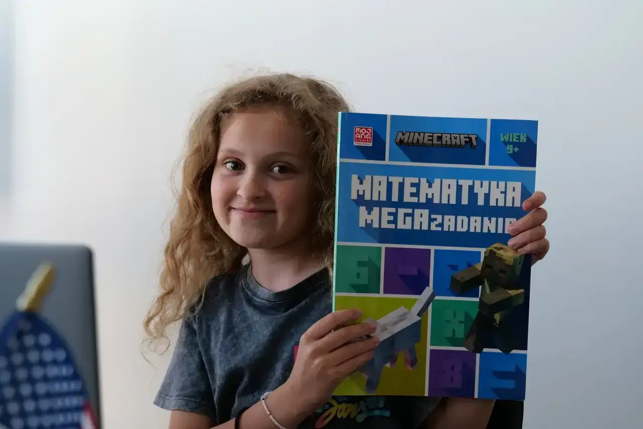 Uśmiechnięta dziewczynka prezentuje książkę 