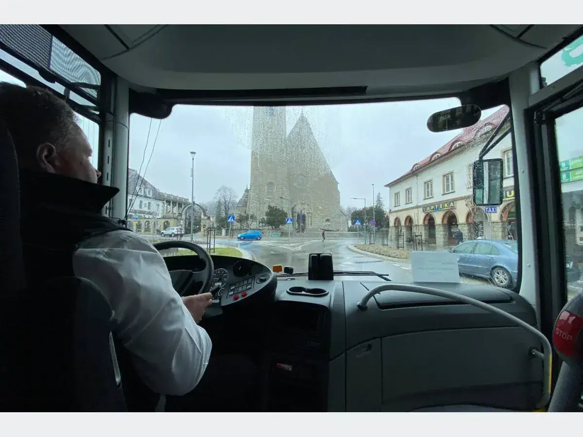 Kierowca autobusu w Limanowej, widok z kabiny na ruchliwą ulicę z kościołem i apteką.
