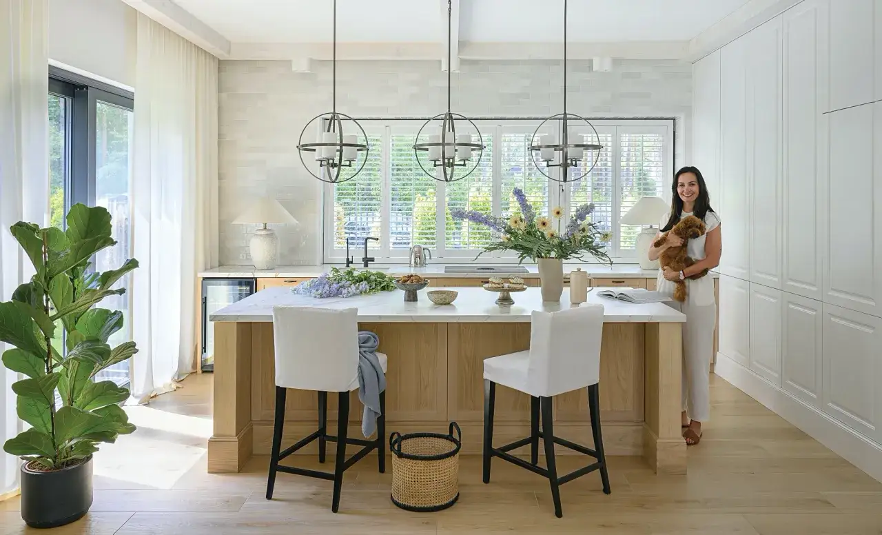 Stylowa lampa nad wyspę loft w kuchni. Kobieta z pieskiem przy wyspie kuchennej.