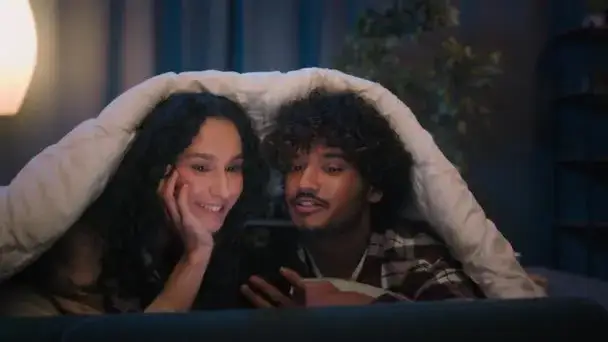 śmiejąca się para w średnim wieku czytająca wiadomość w telefonie