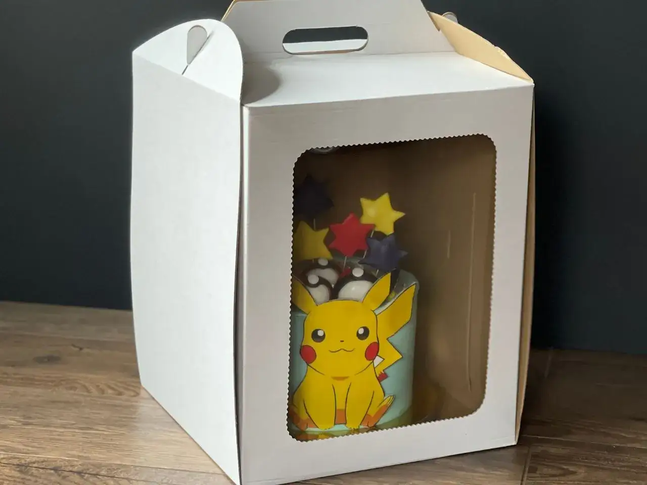 Pudełko z okienkiem, idealne, by bezpiecznie przetransportować tort z Pikachu i gwiazdkami.