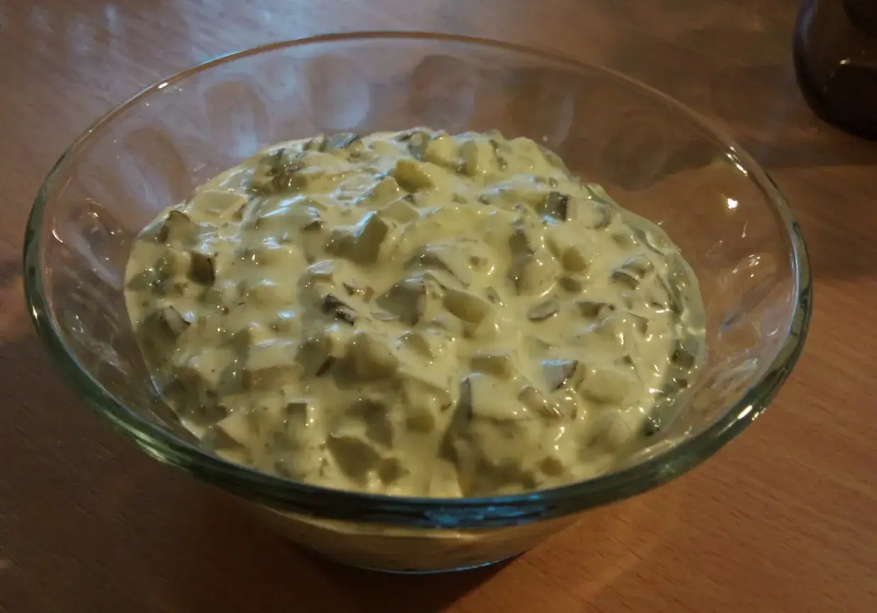 Kremowy sos tatarski w szklanej misce, pełen kawałków ogórka i jajka. Idealny dodatek do wielu dań.