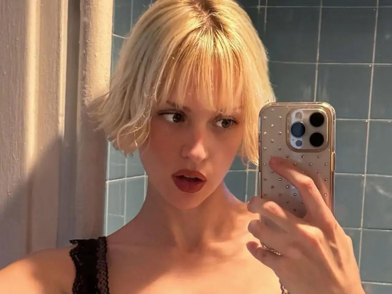 Kobieta z blond włosami w stylu french bob robi selfie w łazience.