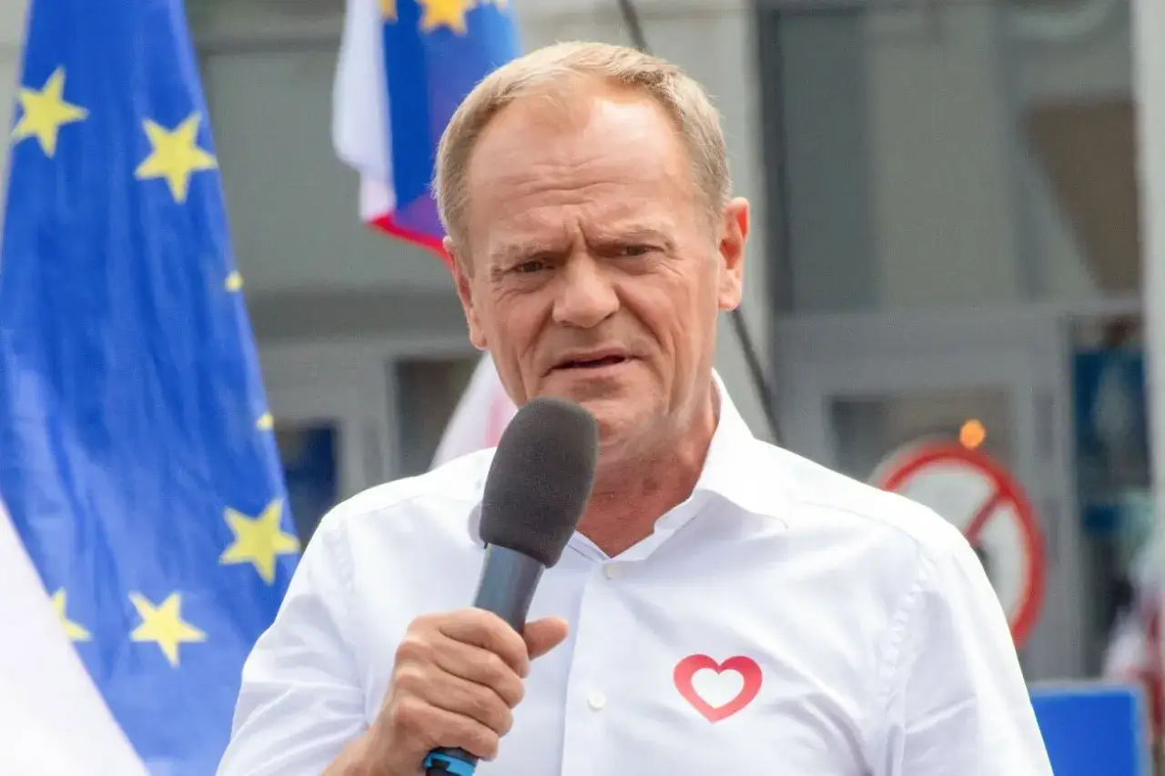 Donald Tusk w Ostródzie, przemawia z mikrofonem, na białej koszuli ma czerwone serce.