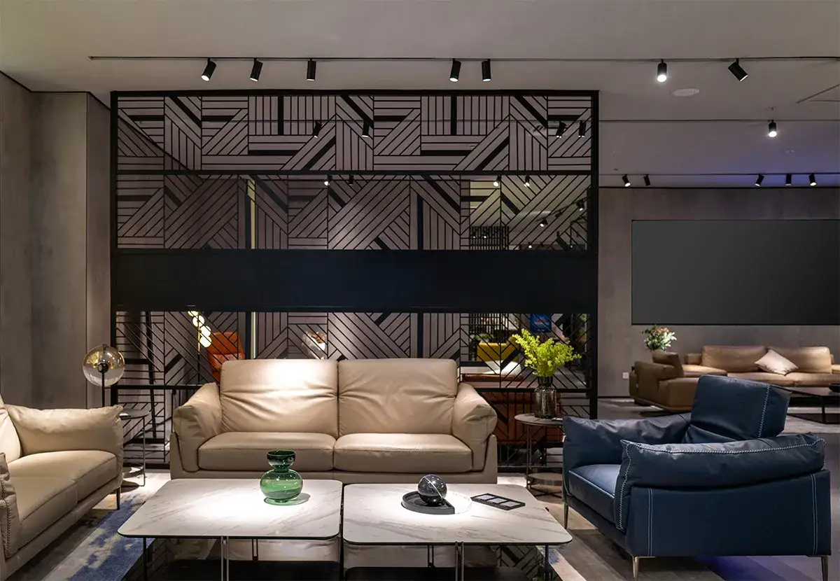 Nowoczesny salon z beżowymi sofami, niebieskim fotelem i stolikami. Nad nimi dyskretne oświetlenie szynowe dwufazowe.