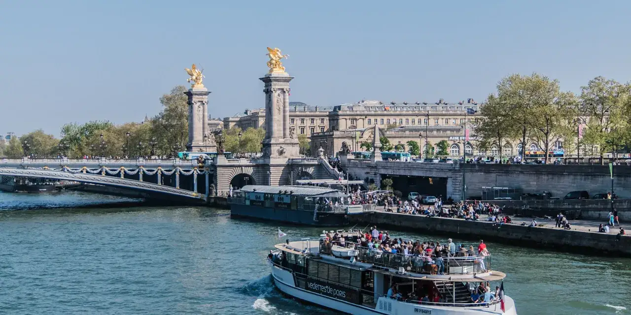 Statek wycieczkowy z turystami płynie Sekwaną, pod mostem Aleksandra III, podziwiając zabytki Paryża.