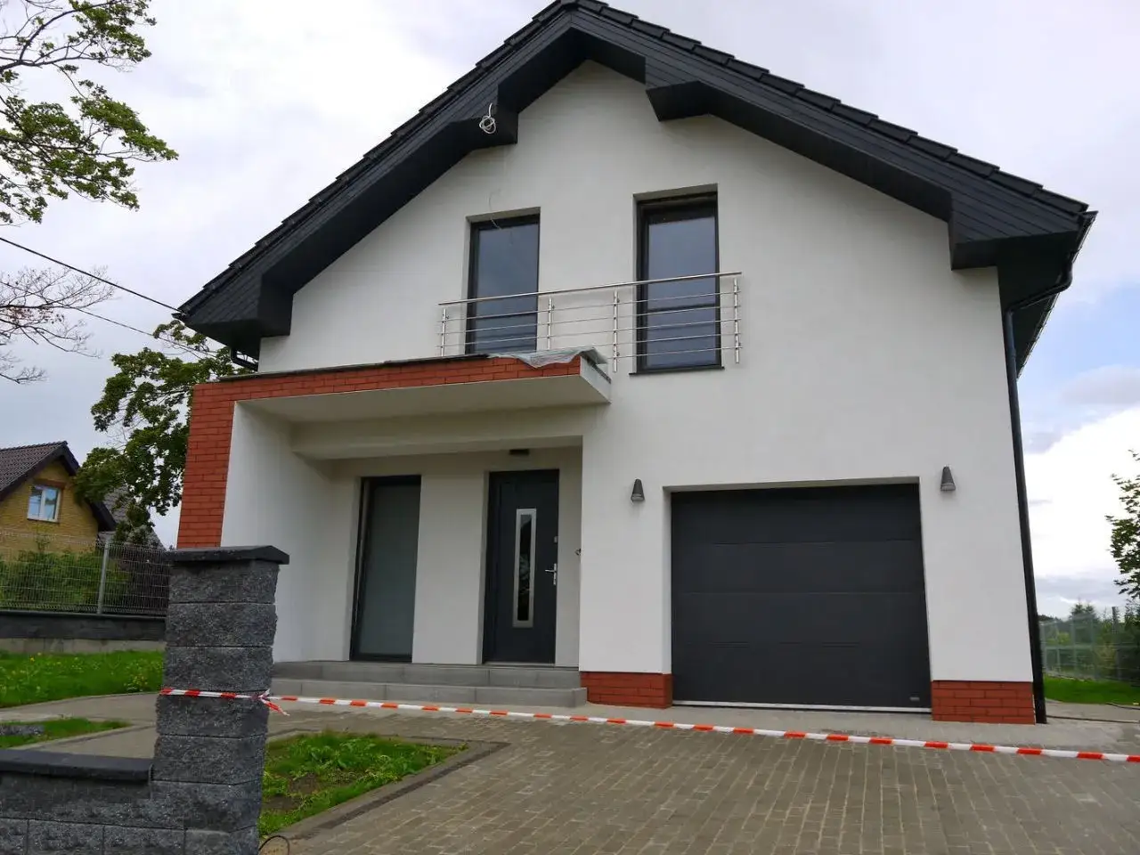 Nowoczesny dom z białym tynkiem, antracytowym dachem i oknami. Elewacja z cegłą klinkierową.