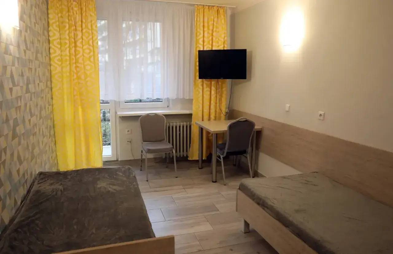 Pokój jednoosobowy w sanatorium: dwa łóżka, stolik, krzesła, TV. Dowiedz się, ile kosztuje pokój jednoosobowy w sanatorium.