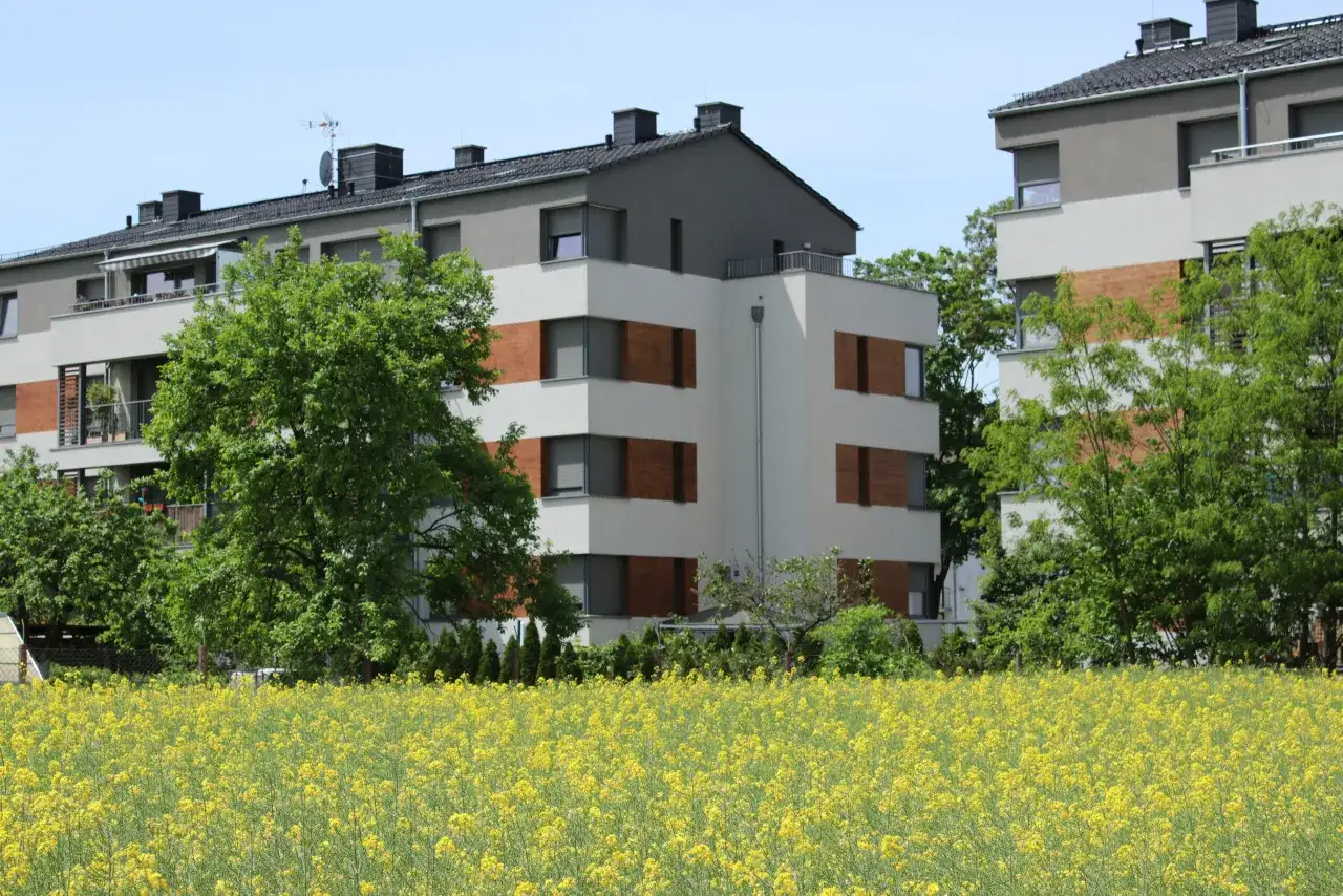 Nowoczesne bloki mieszkalne otoczone zielenią i polem rzepaku. Idealne miejsce na zakup mieszkania z dofinansowaniem.