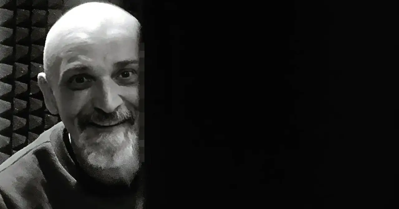 Uśmiechnięty Wojciech Sęp Dudziński, z charakterystyczną brodą i łysą głową, w studiu nagraniowym.