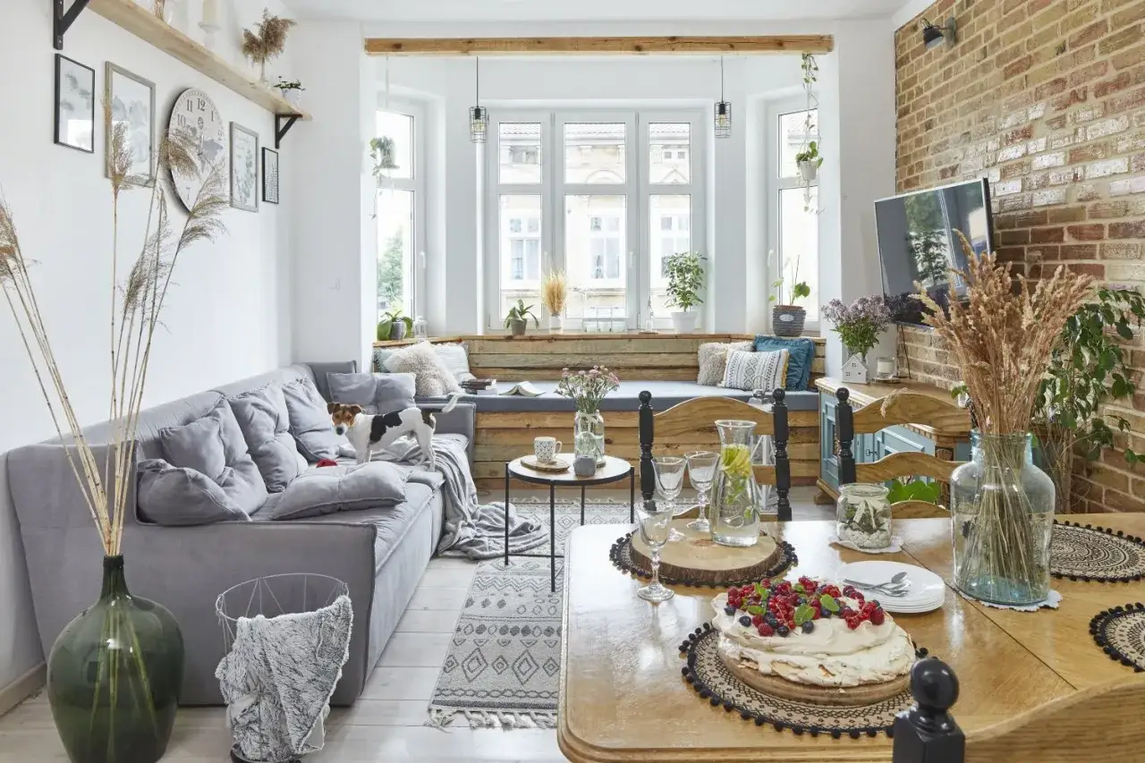 Przytulny salon z szarą kanapą, psem i stołem z tortem. Styl country glam w nowoczesnym wydaniu.