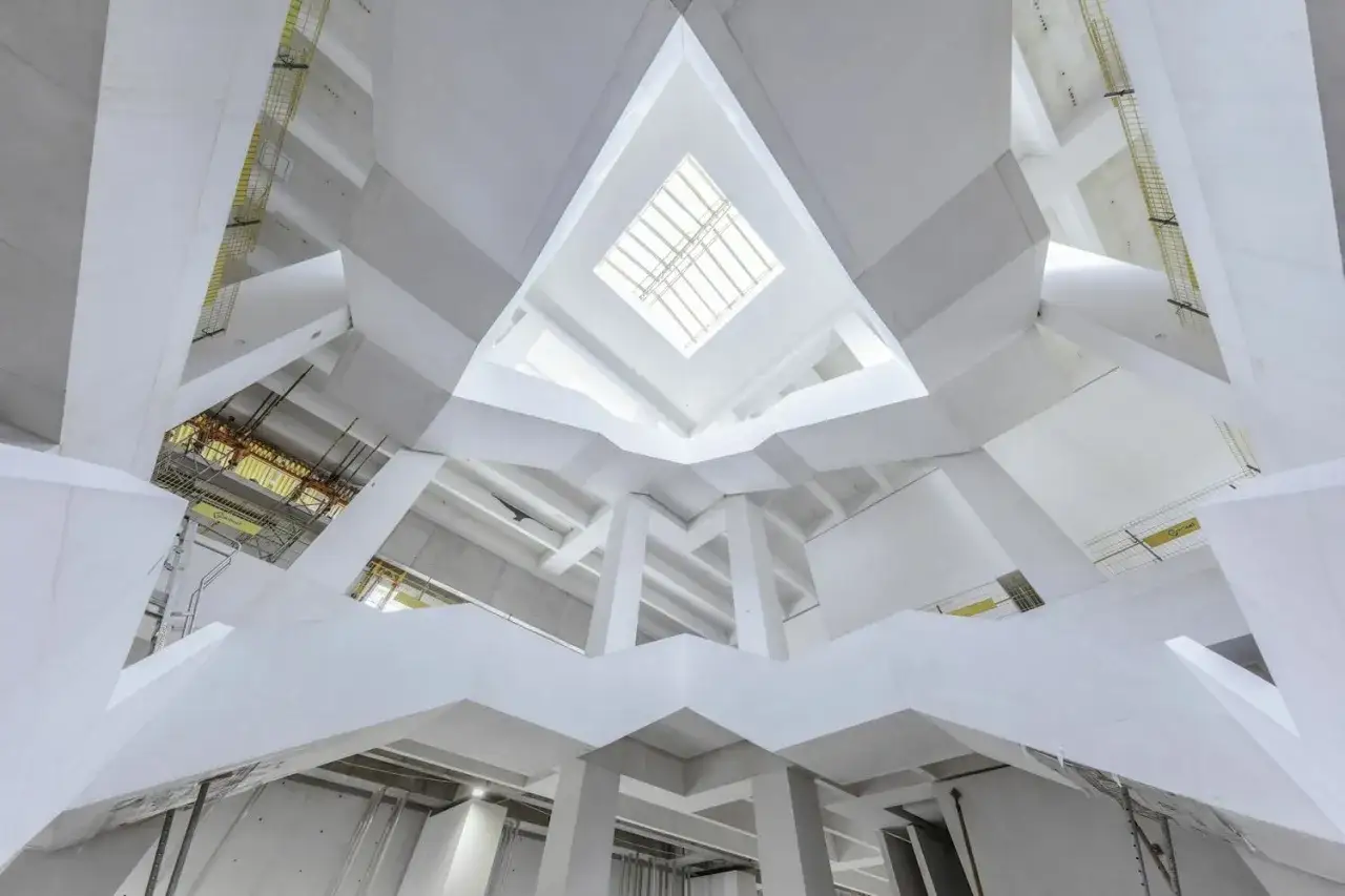 Wnętrze Muzeum Sztuki Nowoczesnej w Warszawie, projekt architektoniczny z białymi, geometrycznymi formami i świetlikiem w centrum.