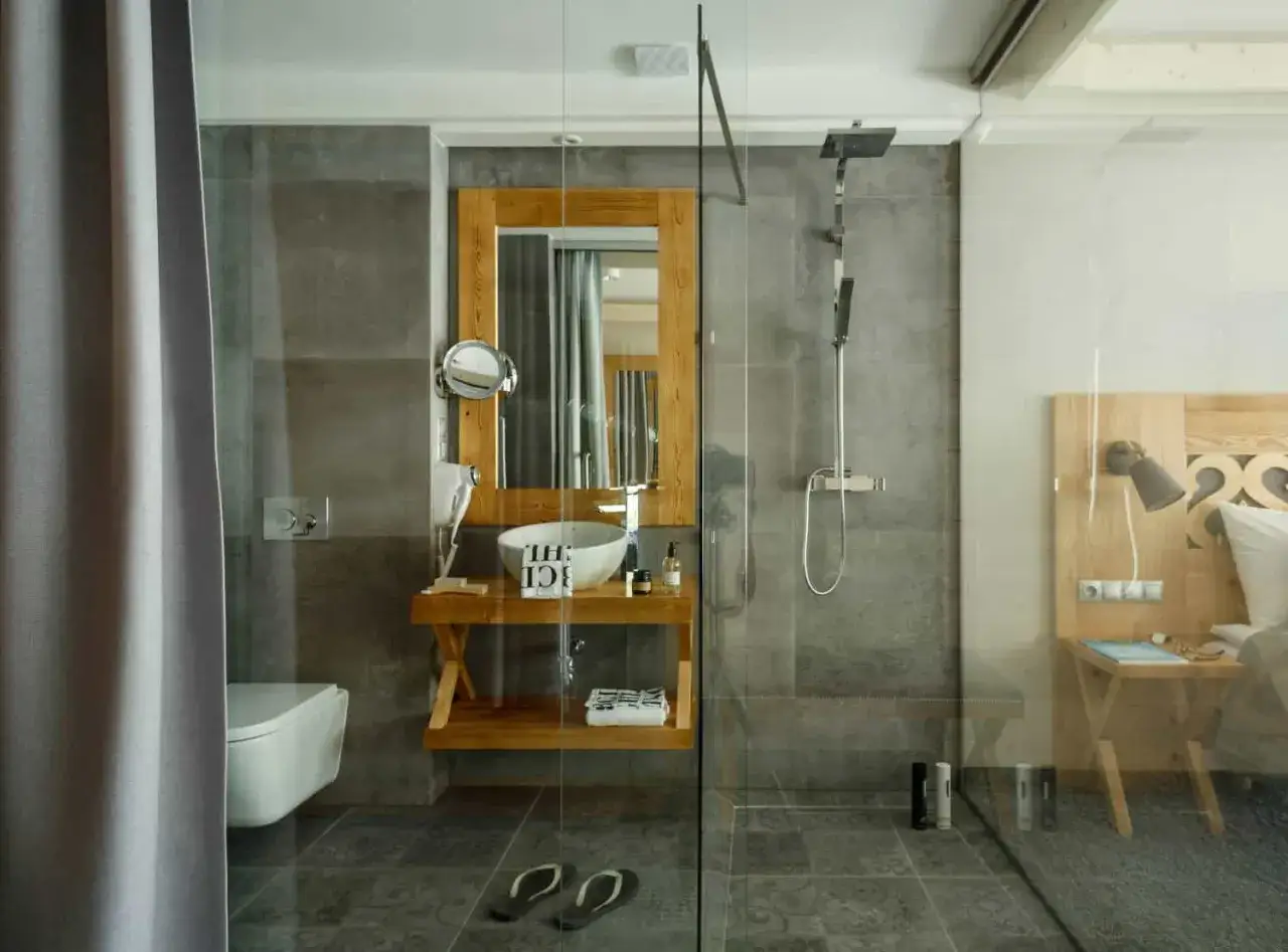 Nowoczesna łazienka w stylu góralskim w Villa Nova Zakopane. Drewno, kamień i szkło tworzą przytulną atmosferę.