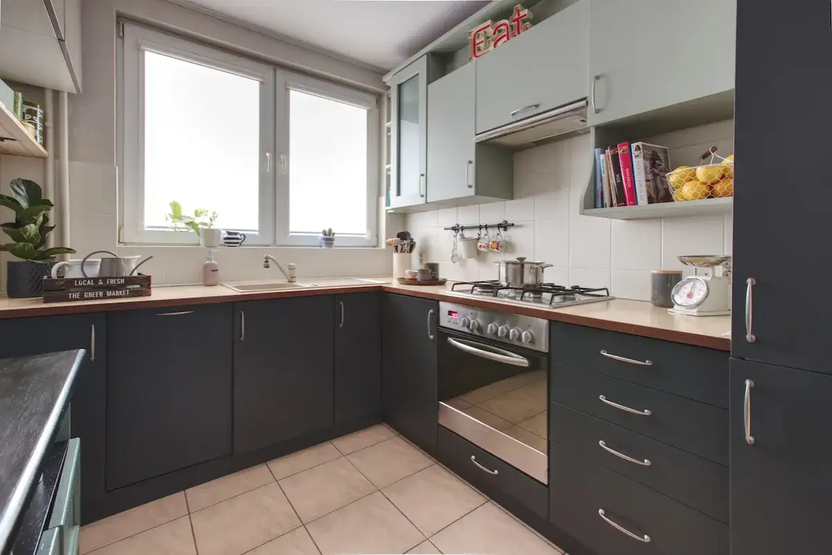 Nowoczesna kuchnia z ciemnymi szafkami i jasnymi blatami. Inspiracja, jak odnowić meble kuchenne, by nadać im świeży wygląd.