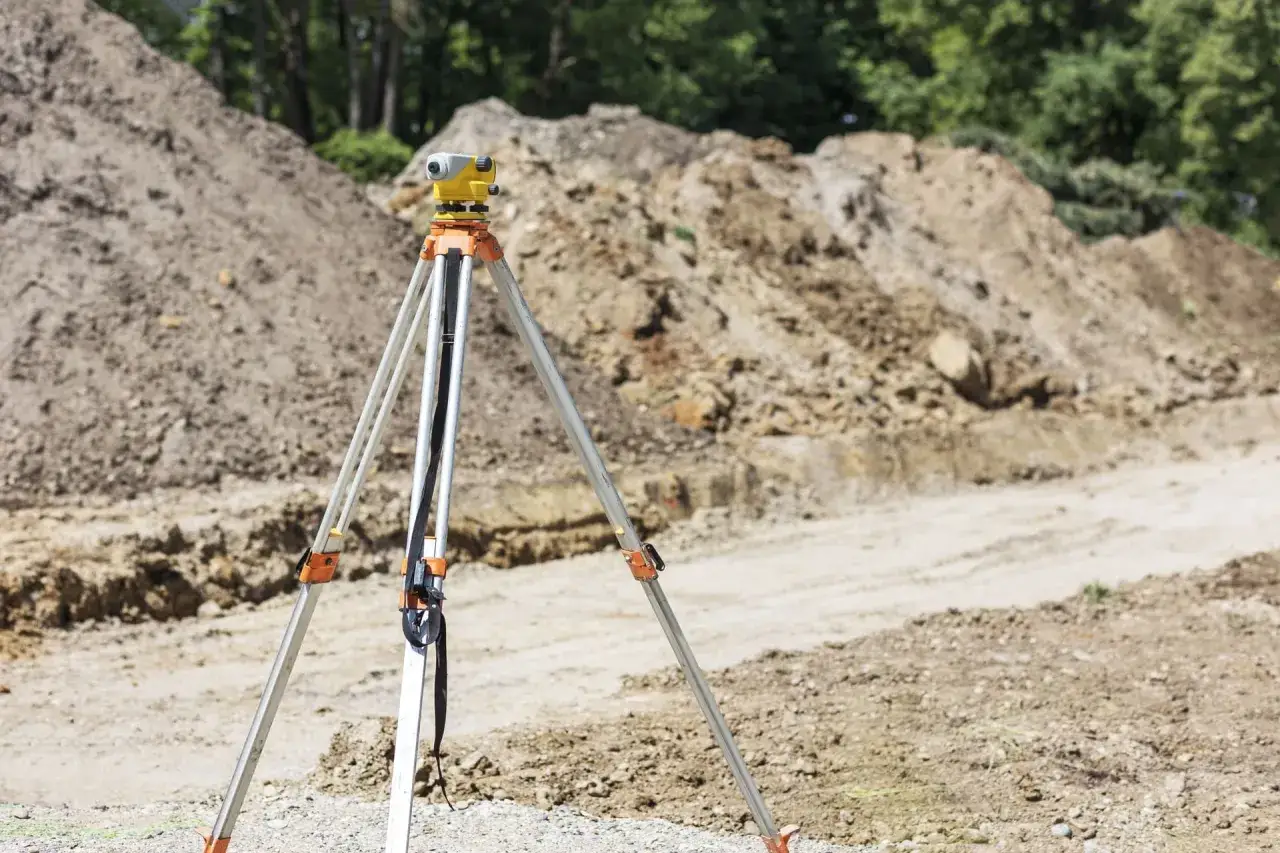 Precyzyjne pomiary geodezyjne to klucz do odpowiedzi na pytanie, ile bierze geodeta za podział działki. Sprzęt geodezyjny na statywie czeka na rozpoczęcie prac.